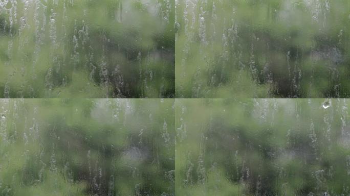 大雨。夏日的雨滴在窗户玻璃上。选择性聚焦，浅景深。水滴落在潮湿的窗户上。倾盆大雨时装满水滴的玻璃。全