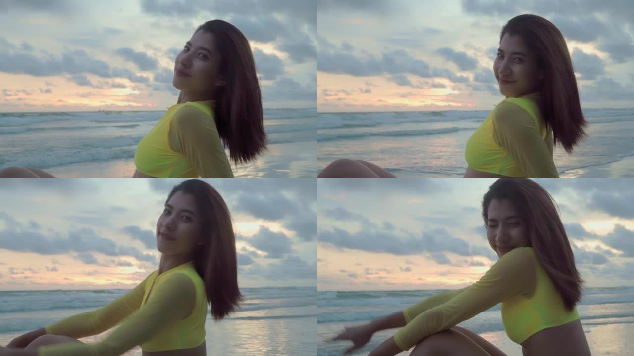 穿着比基尼性感的年轻亚洲女性坐在沙滩上放松夏天，她放松在沙滩上