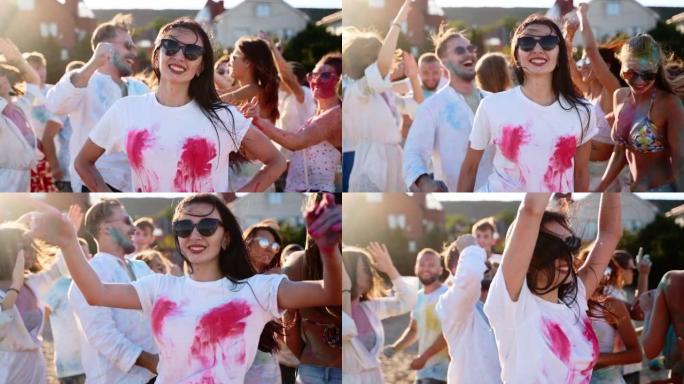 可爱的女人在胸部的白色t恤上溅起彩色粉末。戴墨镜的女孩在洒红节上玩得很开心。人们庆祝印度教节日。封锁