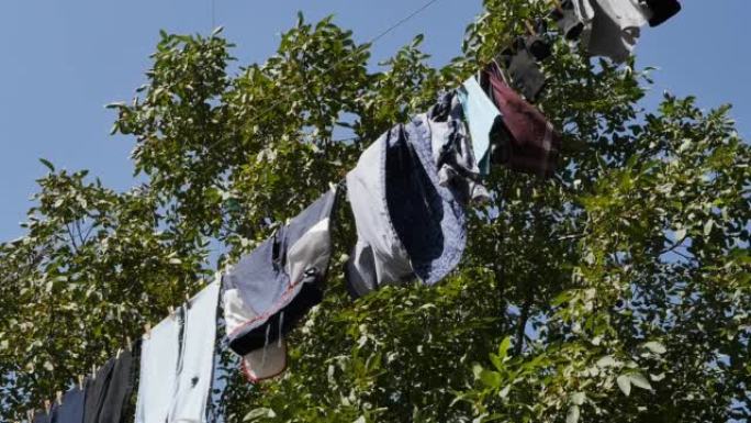 洗过的衣服在房子院子里的绳子上用太阳热在户外晒干，被风吹动。一些发展中国家的户外干燥传统