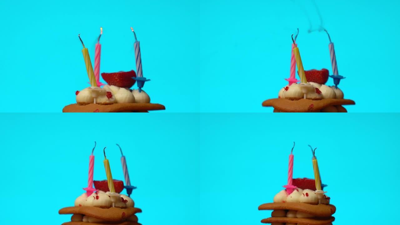 一块蓝色背景上燃烧着蜡烛的生日蛋糕被吹灭了。节日蜡烛在彩虹蛋糕上燃烧