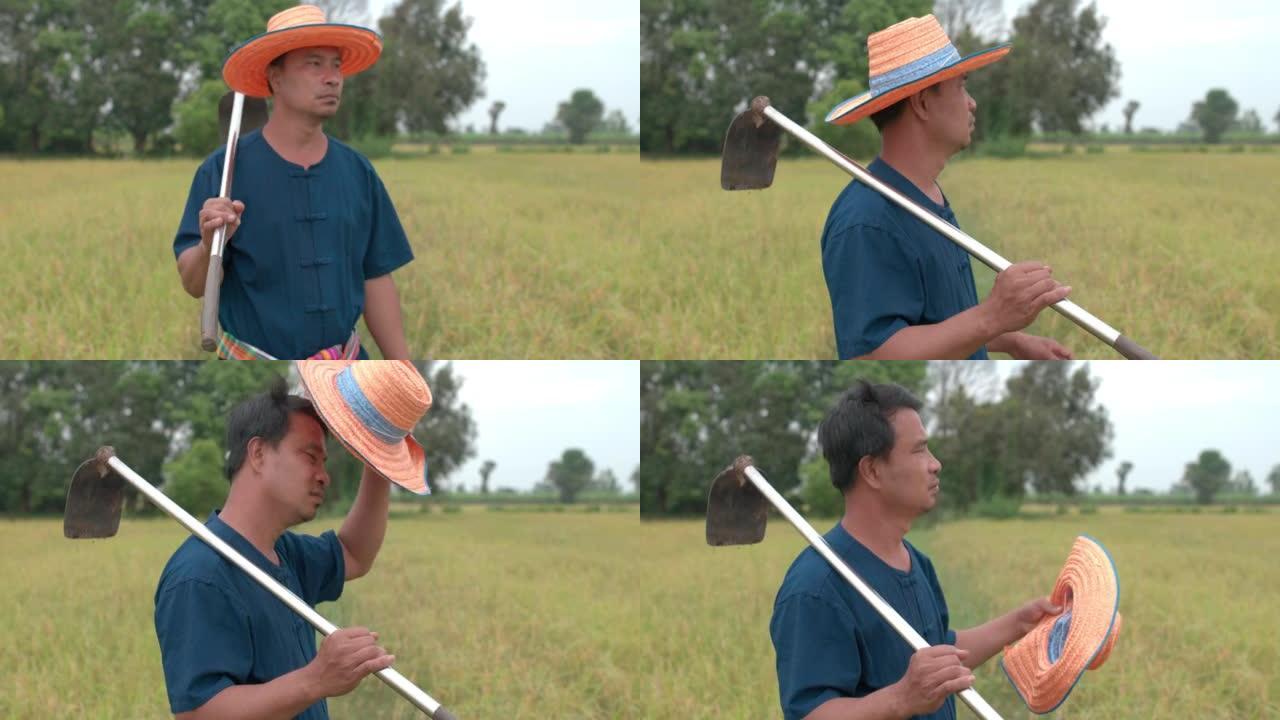 疲惫的亚洲农民男子脱帽拿铁锹