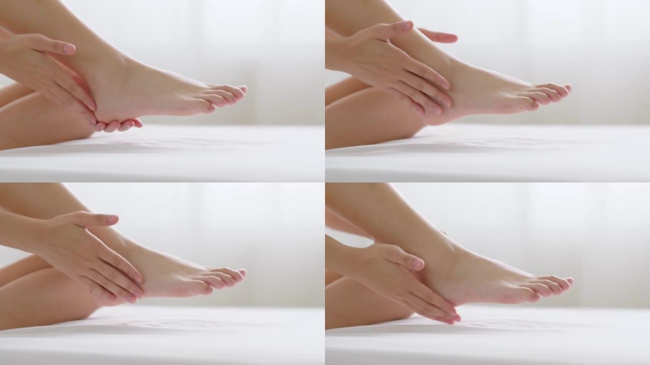 关闭年轻的亚洲妇女使用乳液和护肤霜在脚后跟干燥皮肤