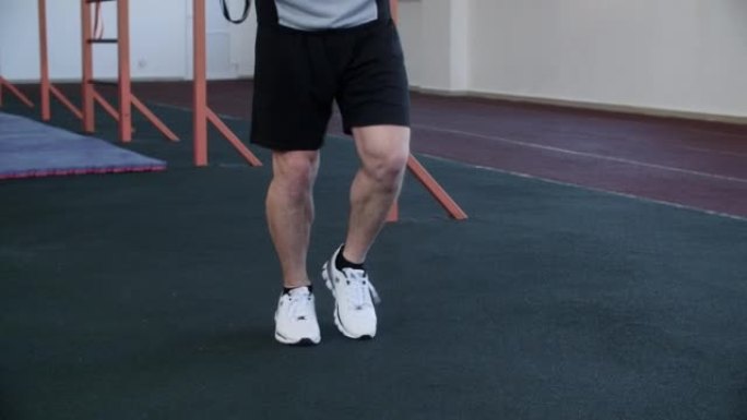 穿着短裤的男人的腿在锻炼前在健身房跳绳。