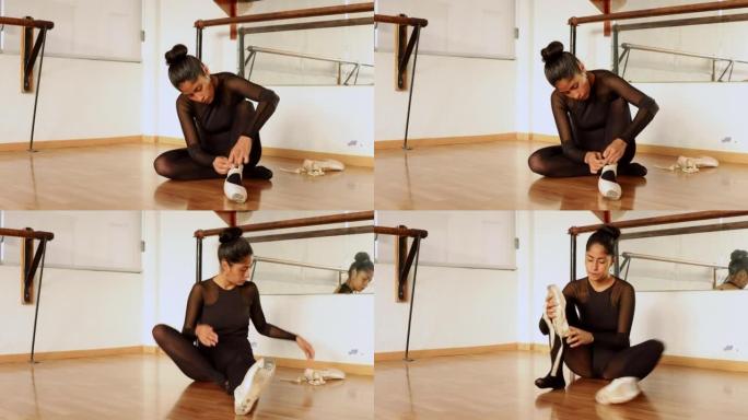 young ballet dancer sitting on the floor lacing up