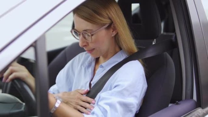 戴眼镜和休闲衬衫的沮丧受惊的女人几乎没有呼吸，坐在车里的肚子突然剧烈疼痛，胃灼热或恶心发作，呼吸困难