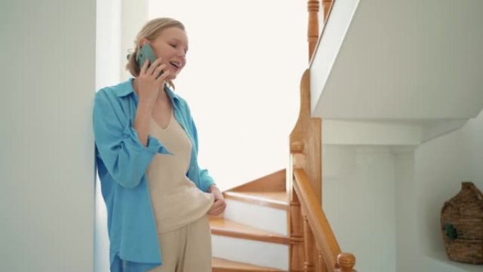 Smiling woman talking by phone indoors at home