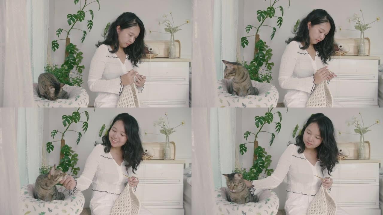 亚洲女人在客厅玩可爱的猫，同时享受钩编。