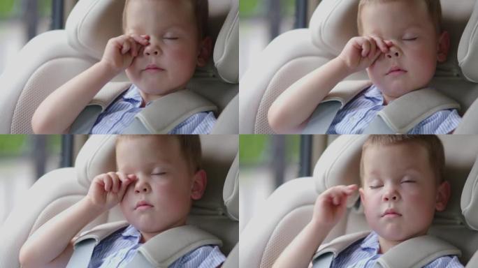 肖像小男孩儿童睡在汽车座椅上，睡在汽车安全座椅上的公路旅行