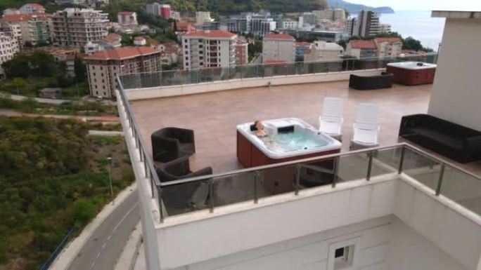 慢动作视频。一名年轻女子的空中射击在屋顶的热水浴缸中放松