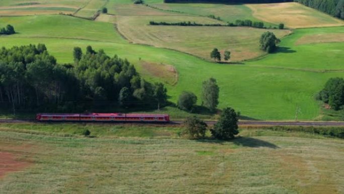 铁路上的红色火车。波兰公共交通基础设施的旅客列车鸟瞰图景观。客运电动火车穿过美丽的欧洲乡村的农田。