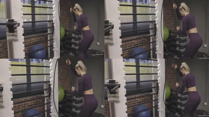 女人在健身房的滑轮上拉橡皮筋，努力恢复