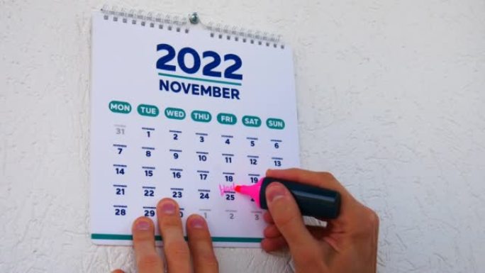 挂历2022的11月页，男性用记号笔标记黑色星期五日期