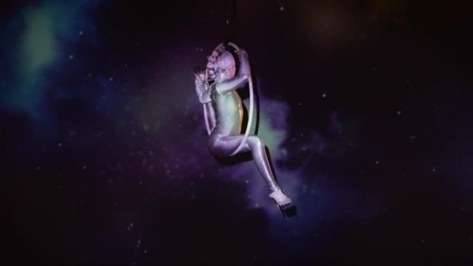 灵活的女性柔术师在太空背景下的空气箍上表演