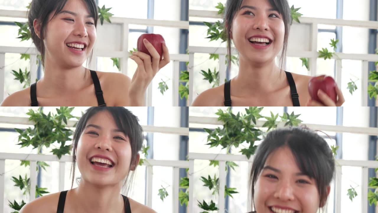 年轻的亚洲妇女吃苹果健康。女孩锻炼拿着有机苹果水果健康的生活方式。健康亚洲女性吃红苹果笑脸看相机。美