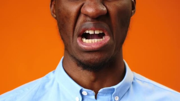 非洲男子的特写脸在橙色背景下移动嘴唇