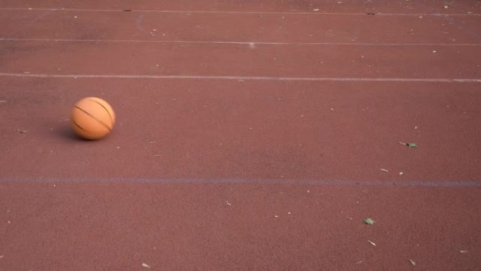 Basketball ball rolls through outdoor red street c