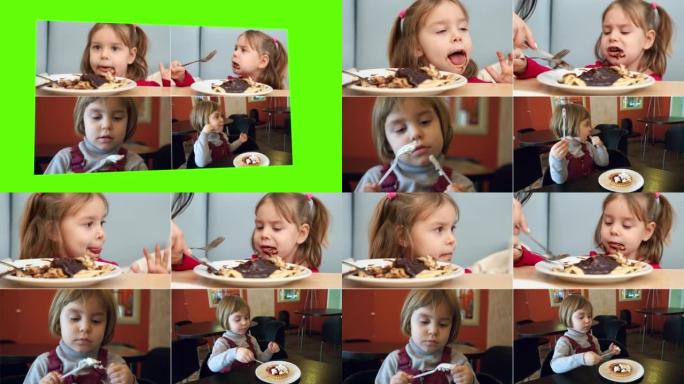 一个金发碧眼的孩子，坐在美食广场或咖啡馆的桌子旁，吃得很有趣。甜食，甜点概念。小女孩吃巧克力煎饼。分