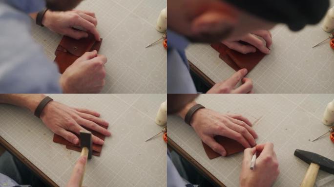 皮革工匠在他的车间工作。制作皮革双折钱包的大师。男人将胶水涂在硬币口袋的形状上，然后粘在一起，然后用