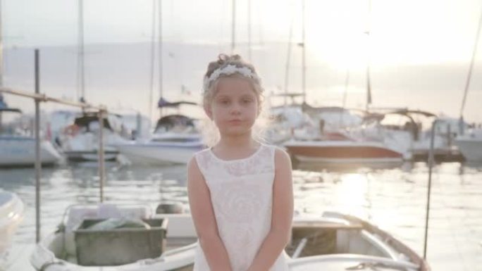 Little girl stops at sunset in front of the boats