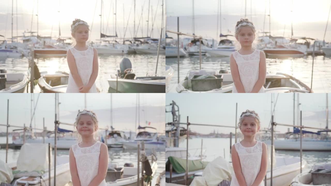 Little girl stops at sunset in front of the boats