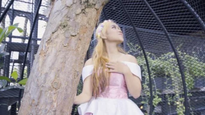 公主坐在笼子里，花园里有一棵树