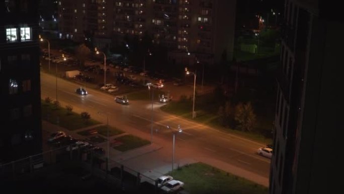 慢动作拍摄有汽车的柏油路和夜间多层建筑的城市景观。夜城中的现代建筑。