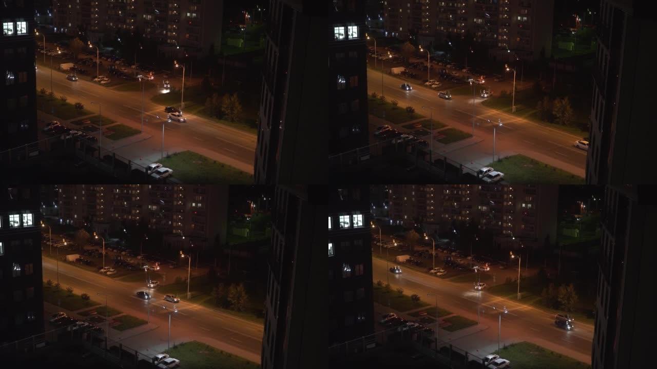 慢动作拍摄有汽车的柏油路和夜间多层建筑的城市景观。夜城中的现代建筑。