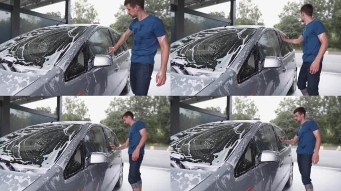 自助洗车场的一男一女。快乐的夫妇在阳光明媚的日子洗车，在院子里玩得开心。女孩和男孩在压力下用泡沫和水