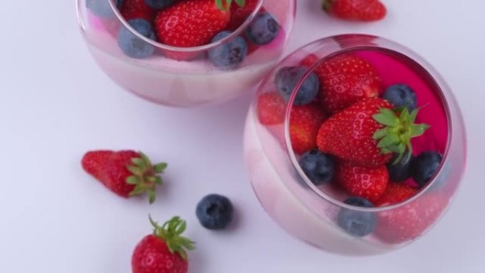 水果果冻甜点或奶油奶油与新鲜草莓和蓝莓旋转，顶视图，白色背景