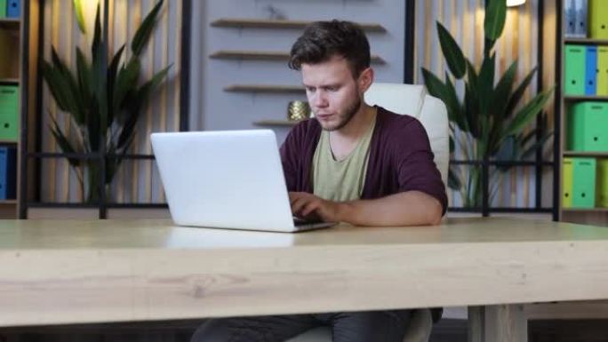 男性IT行业工作人员在现代舒适办公室的笔记本电脑上工作。