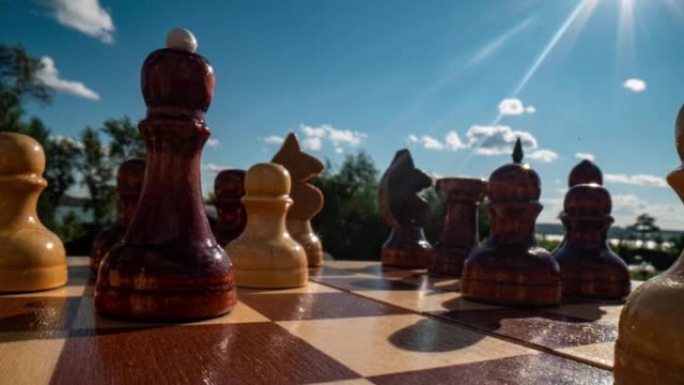 近景多利微距镜头的一个白色木制国际象棋皇后在棋盘上。平滑的相机运动上面的棋盘与黑白棋子。黑色背景。