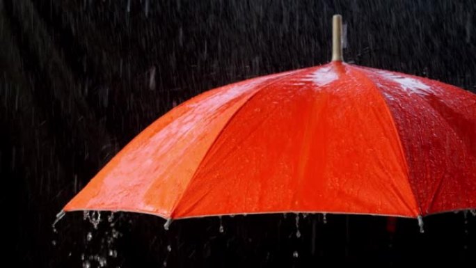 黑色双面伞上的橙色雨伞上的雨滴。