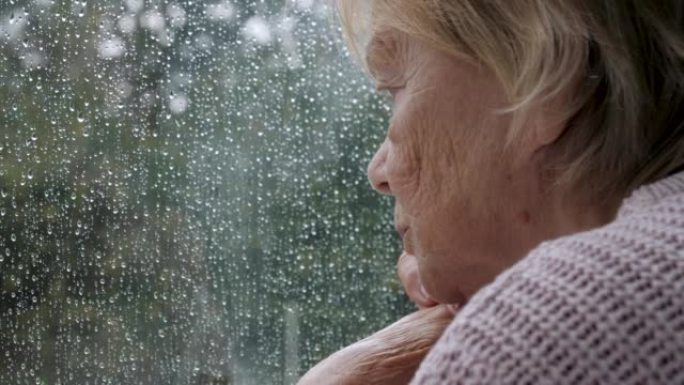 悲伤的老妇希望在雨中走出窗外