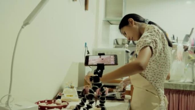 女孩在家里的厨房里用智能手机制作视频烹饪巧克力大福Mochi (日本小吃)，生活方式概念。