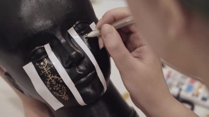 女人用金铅笔画符文人体模型的黑头。