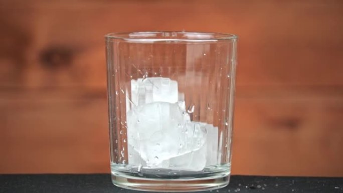 冰与鸡尾酒一起落入玻璃杯中冷却饮料