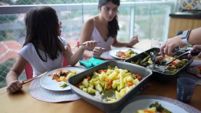 家庭在家吃午餐。母女俩围坐在食物周围。人们聚集在一起