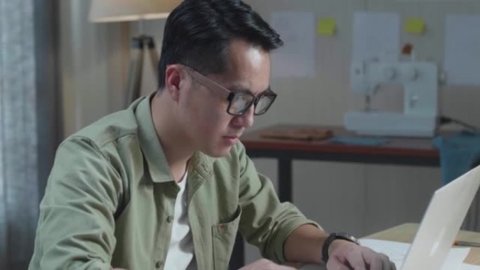 在办公室使用笔记本电脑进行布局结合的亚洲男包设计师的特写