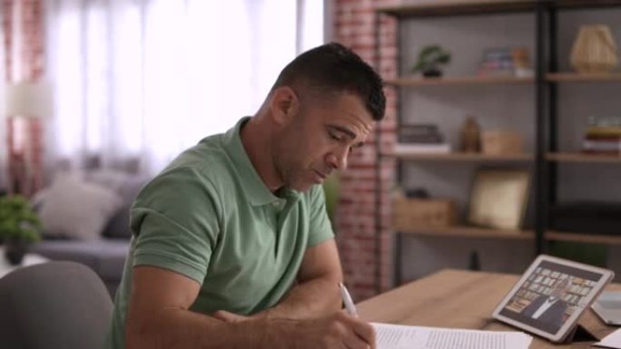 男人在家时在数字平板电脑上进行在线学习。