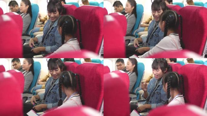 亚洲母亲坐在飞机上给女儿第一次飞行的建议，乘飞机去度假旅行。航空运输概念