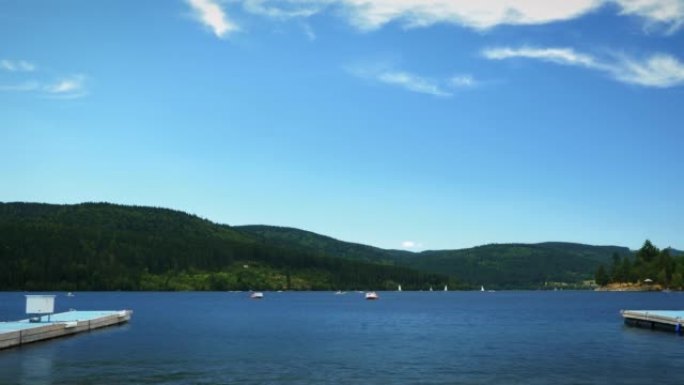 湖泊的时光倒流被绿树和群山环绕，有漂浮的船和船。周末人们在湖上休息。阳光明媚的夏日，有游艇、船只和船