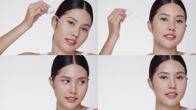 年轻的亚洲美女把血清滴在脸上。女人把抗衰老保湿血清放在眼下区域。美容疗法概念。