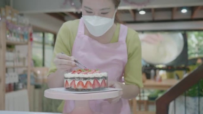 专业厨师正在烹饪蛋糕。在现代厨房中关闭带有草莓的白色蛋糕