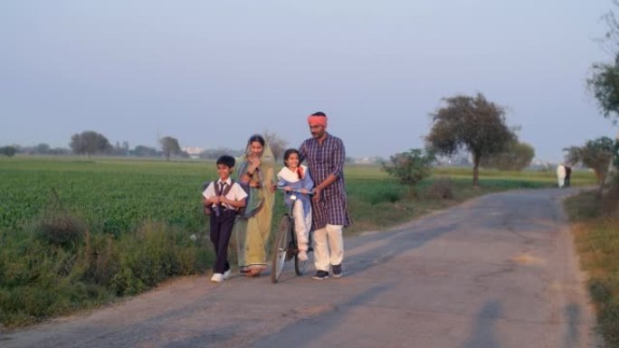 印度一个村庄里的一个小家庭——骑自行车送孩子上学的乡村夫妇