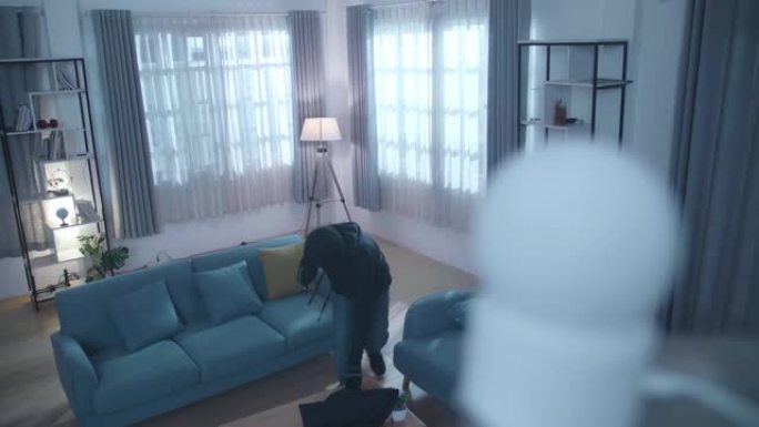 带手电筒的小偷在某人的房子里散步时，将黑色织物覆盖在闭路电视摄像机上