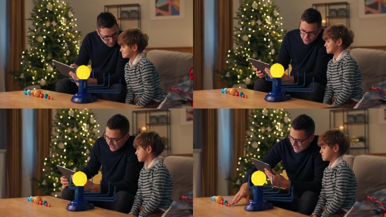 父亲在圣诞节晚上教孩子在平板电脑上查看玩具说明，发光的太阳系模型，在适当的地方安排行星