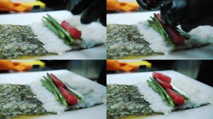 寿司。日本食物。烹饪。烹饪。寿司厨师正在用竹席制作寿司卷。寿司配奶油芝士和鱼配料，米饭，紫菜。特写。