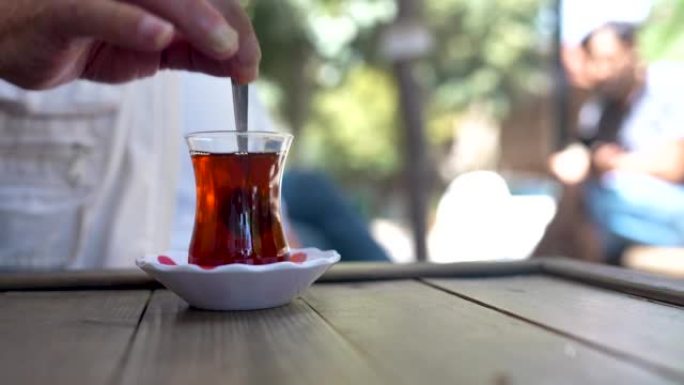 老人把糖放进茶里搅拌。喝传统土耳其茶