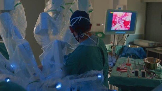 护士在手术期间看着监视器，而外科医生切除肿瘤。现代医疗设备。外科医生助理护士